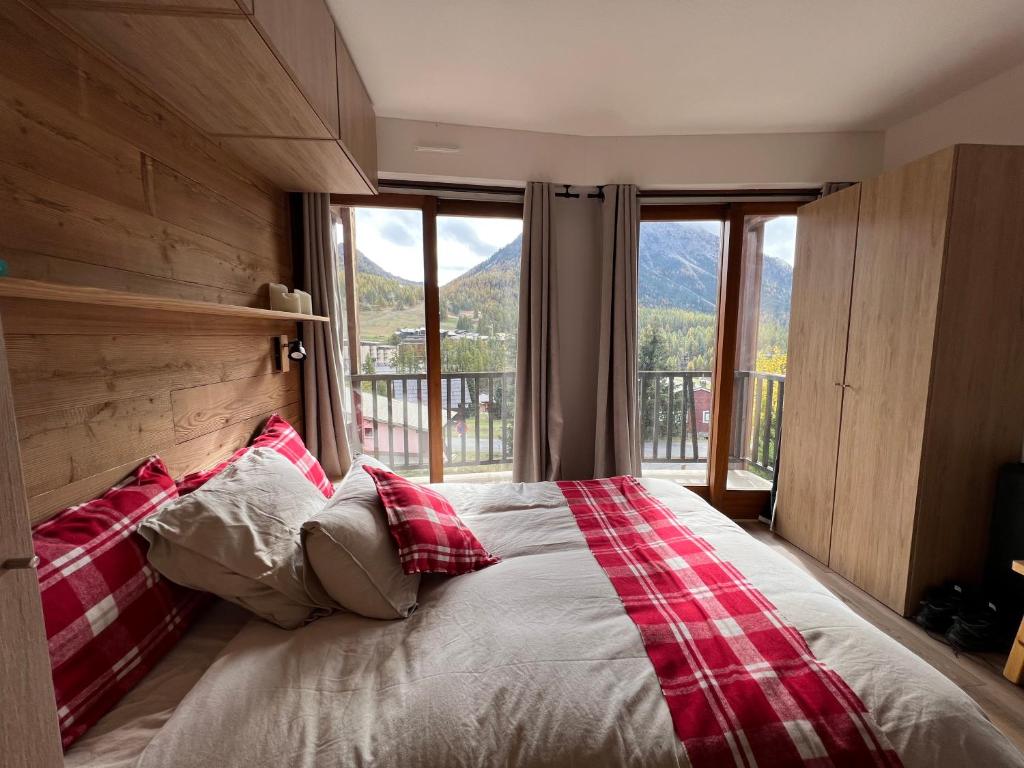 une chambre avec un grand lit avec une grande fenêtre dans l'établissement Les Tanières de Montgenèvre - La Marmotte - Duplex 4 p entièrement rénové avec vue magnifique, à Montgenèvre