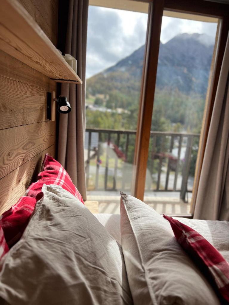 - un lit avec des oreillers devant une fenêtre dans l'établissement Les Tanières de Montgenèvre - La Marmotte - Duplex 4 p entièrement rénové avec vue magnifique, à Montgenèvre