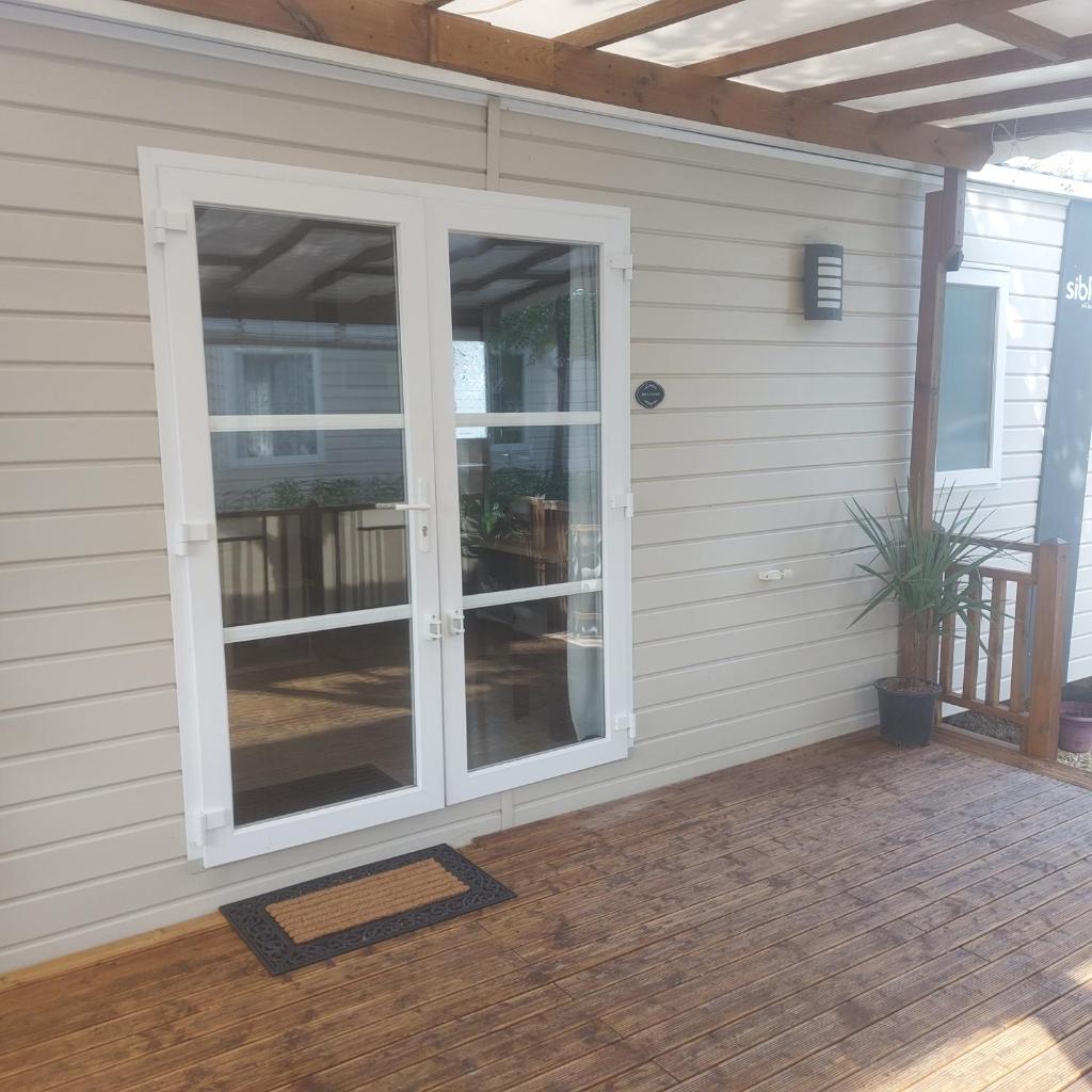 une porte coulissante en verre sur le côté de la maison dans l'établissement Mobil-home à valras-plage au Camping les sables du Midi, à Sérignan