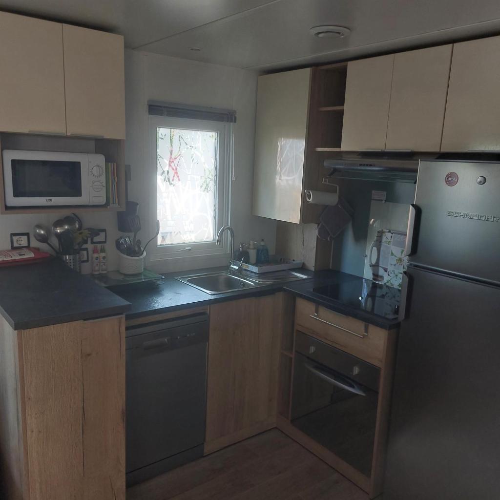 une cuisine avec un évier et un réfrigérateur dans l'établissement Mobil-home à valras-plage au Camping les sables du Midi, à Sérignan