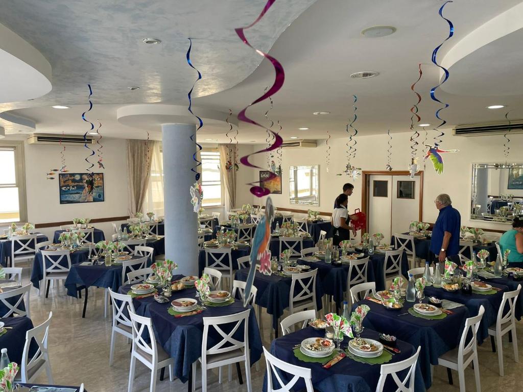 une salle de banquet avec des tables bleues et des chaises avec des cerfs-volants dans l'établissement Hotel Tre Stelle, à Rimini 43 autres photos