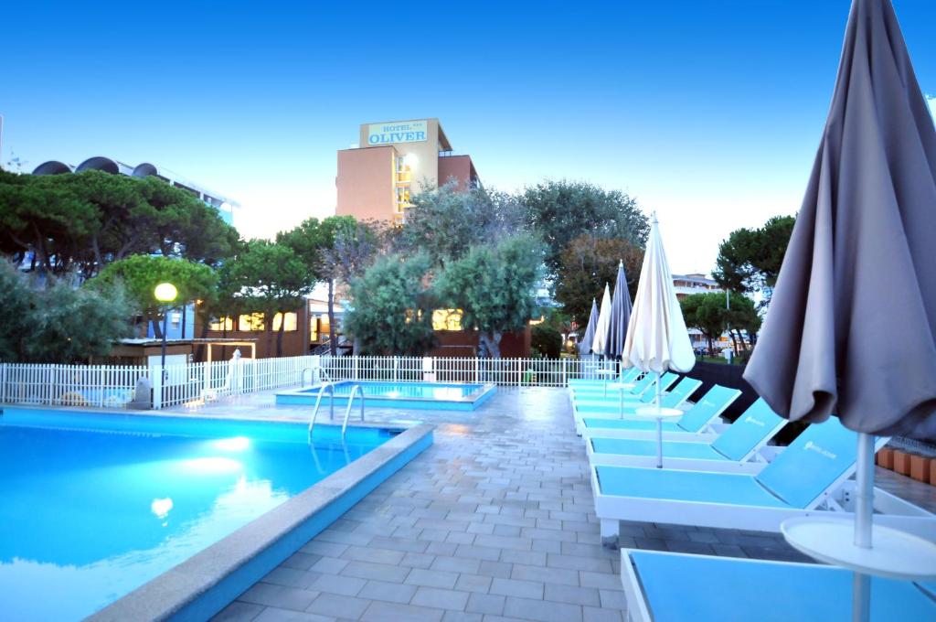 - une piscine avec des chaises et des parasols dans un complexe dans l'établissement Hotel Oliver, à Caorle