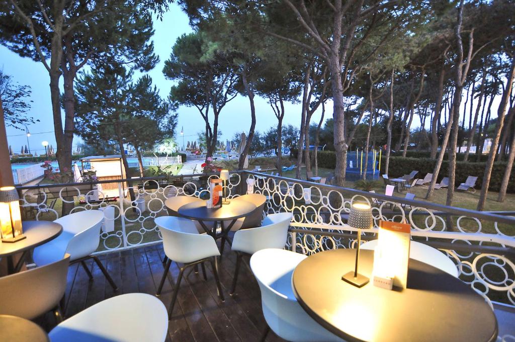 un patio avec des tables et des chaises blanches et des arbres dans l'établissement Hotel Oliver, à Caorle