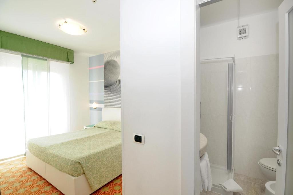 une chambre avec un lit et une salle de bain avec douche dans l'établissement Hotel Oliver, à Caorle