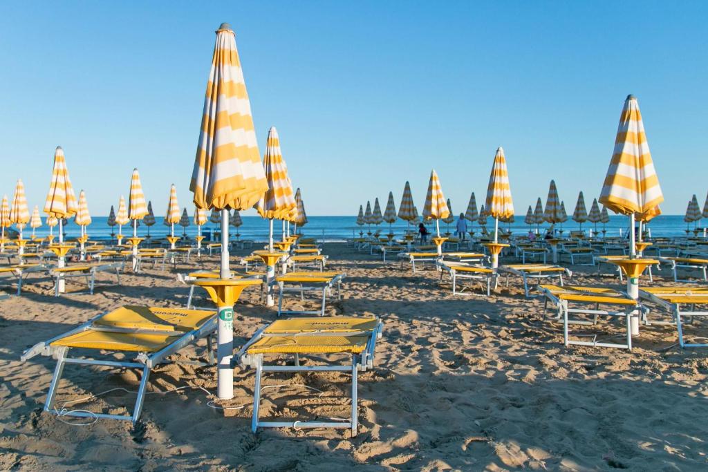 - un bouquet de chaises et de parasols sur une plage dans l'établissement Hotel Ragno, à Lido di Jesolo