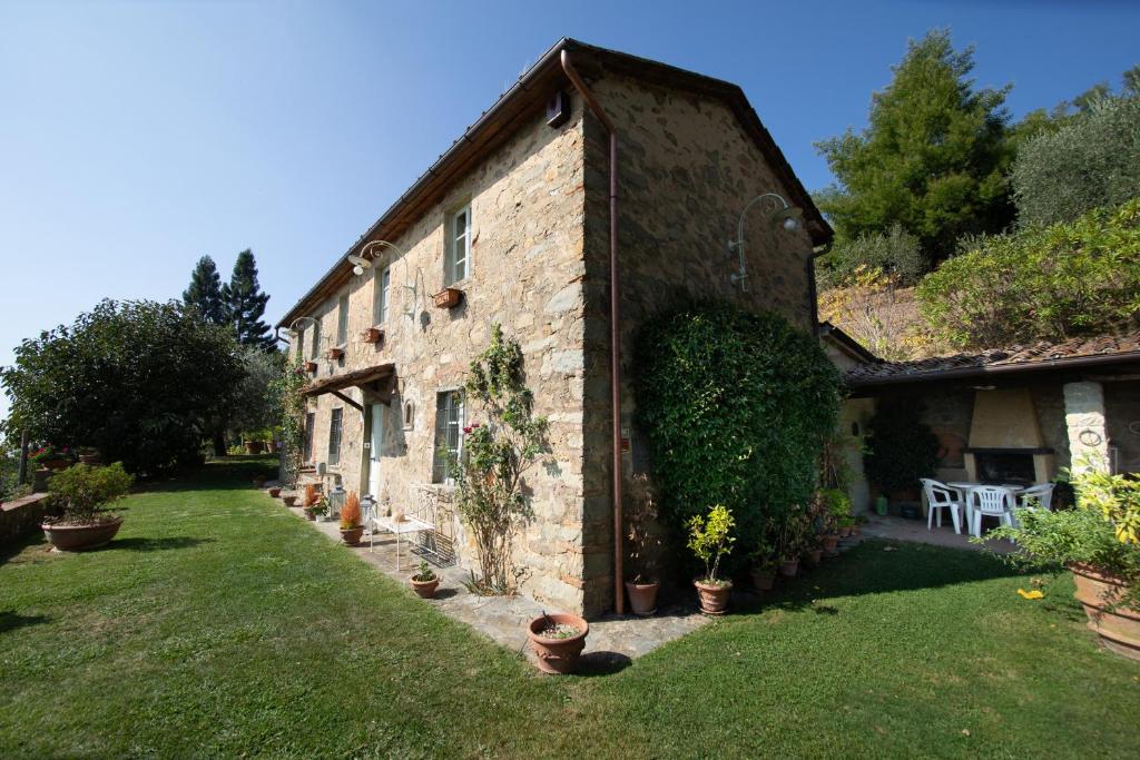 un vieux bâtiment en pierre avec des plantes dans une cour dans l'établissement Villa Iris with Swimming Pool, à Capannori