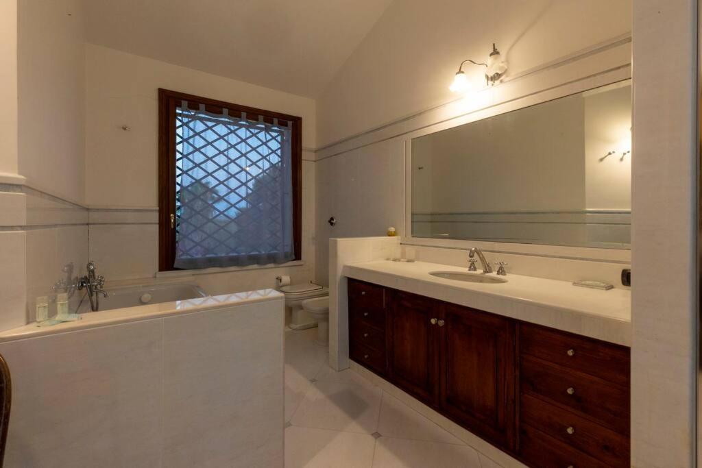 une salle de bain avec deux lavabos, une baignoire et un miroir dans l'établissement A lume di candele, à Paceco