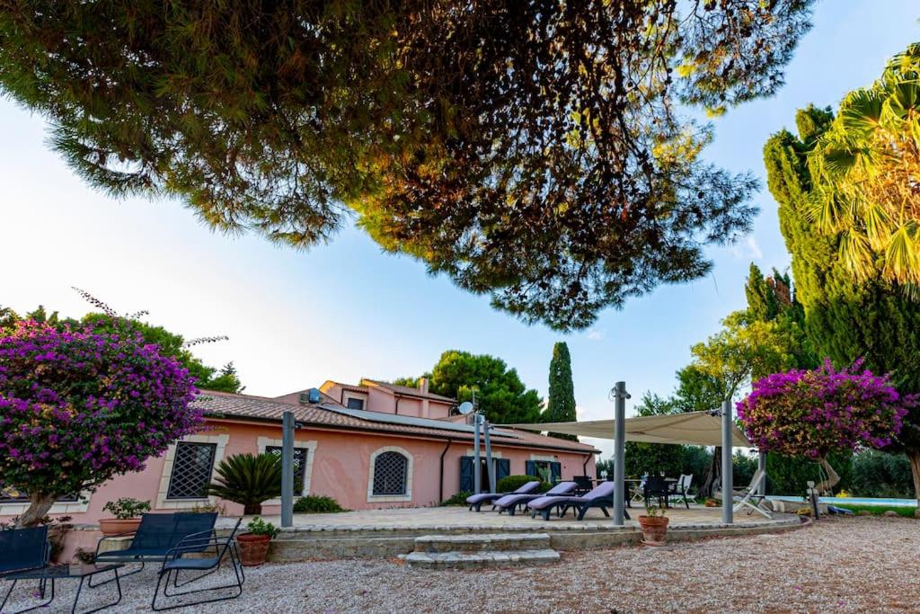 une maison rose avec des chaises bleues devant elle dans l'établissement A lume di candele, à Paceco