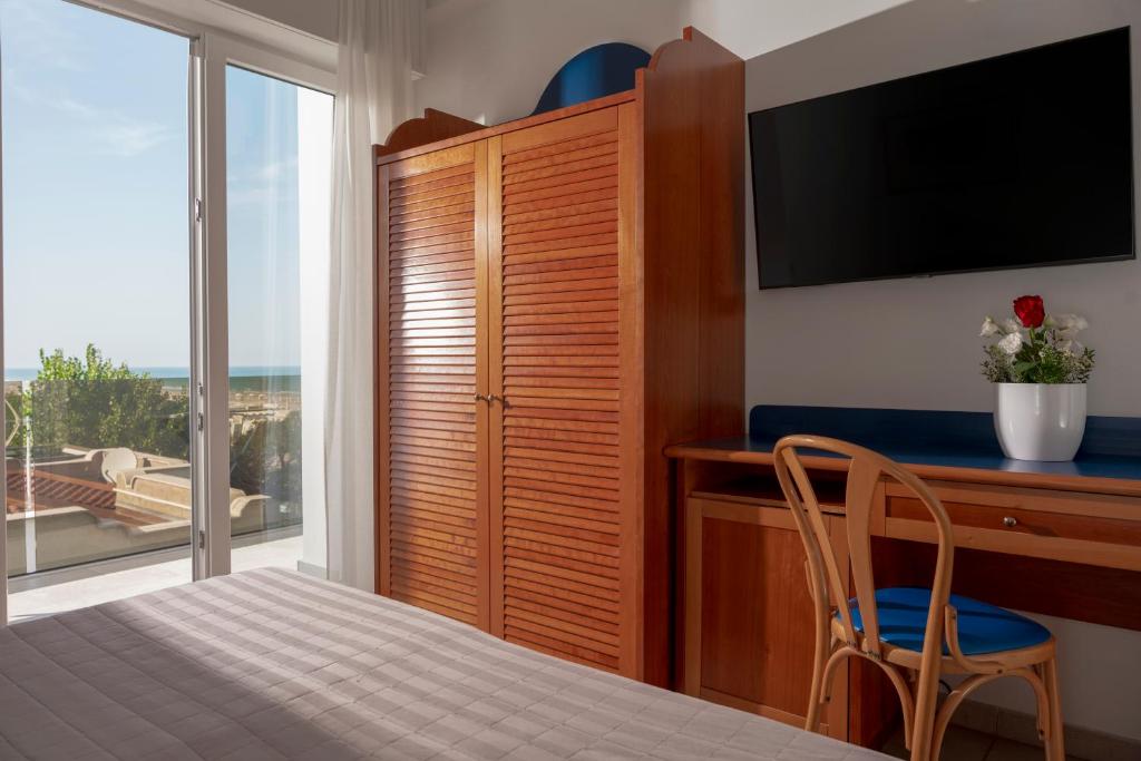 une chambre avec un lit, un bureau et une télévision dans l'établissement Hotel Ascot Riccione, à Riccione