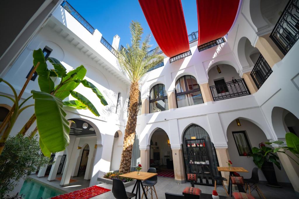 une cour avec un palmier dans un bâtiment dans l'établissement Riad Shanima SPA Marrakech, à Marrakech
