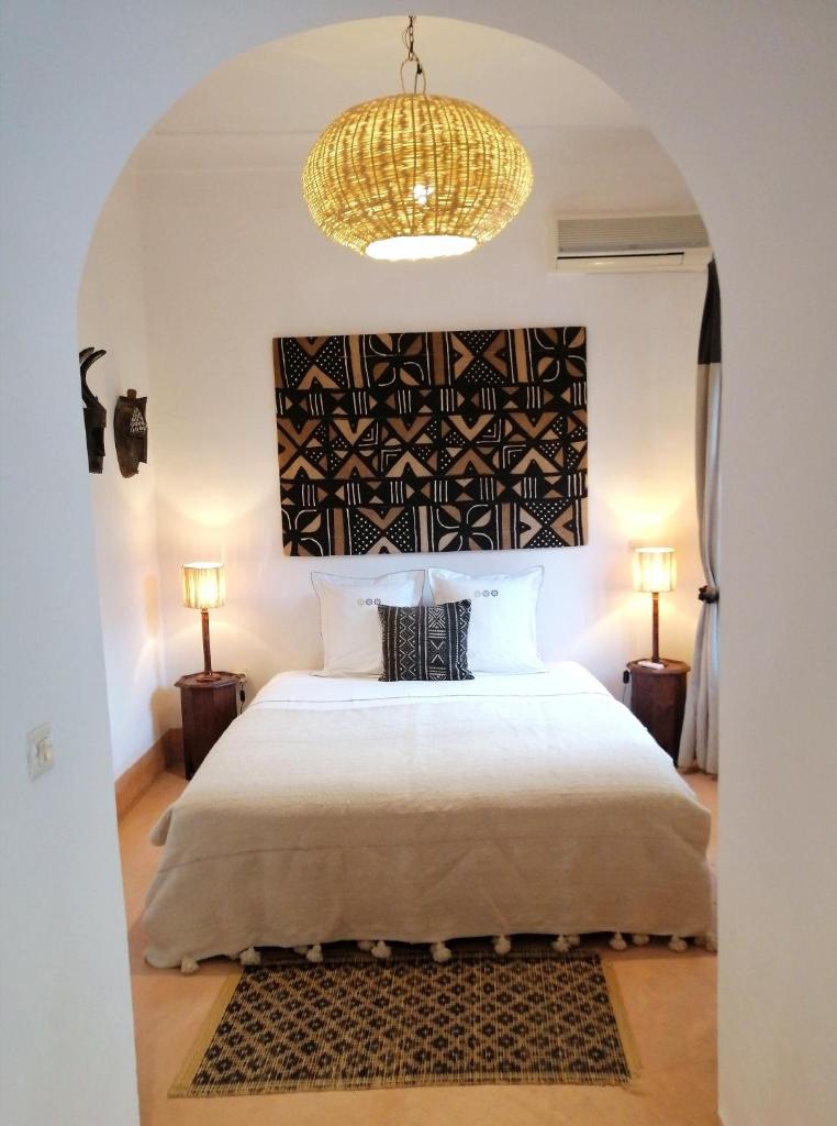 une chambre avec un grand lit et un lustre dans l'établissement Riad Dar Nouba, à Marrakech