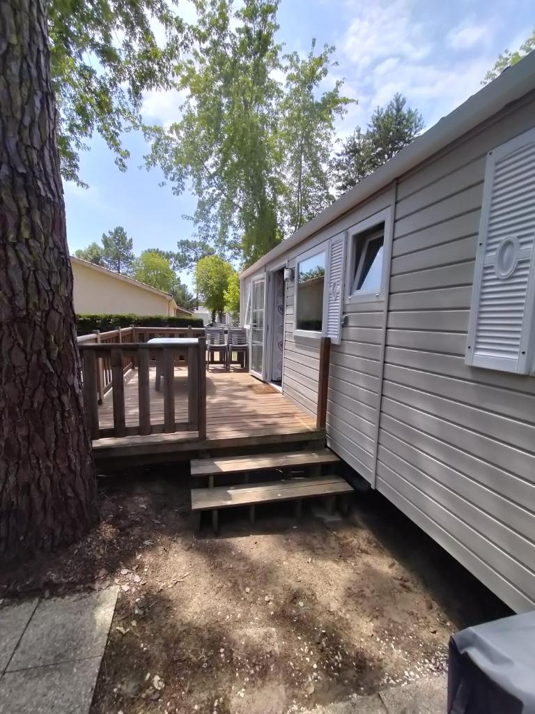 un mobile home avec une terrasse à côté d'un arbre dans l'établissement Mobil home 6 à 8 personnes camping le bois dormant, à Saint-Jean-de-Monts
