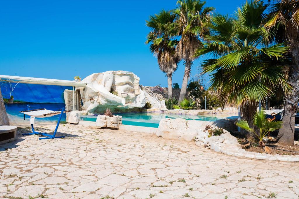 une piscine de villégiature avec des palmiers et un toboggan aquatique dans l'établissement Il Trullo al Mare -Trullo by the sea- Pool & Beach, à Molfetta