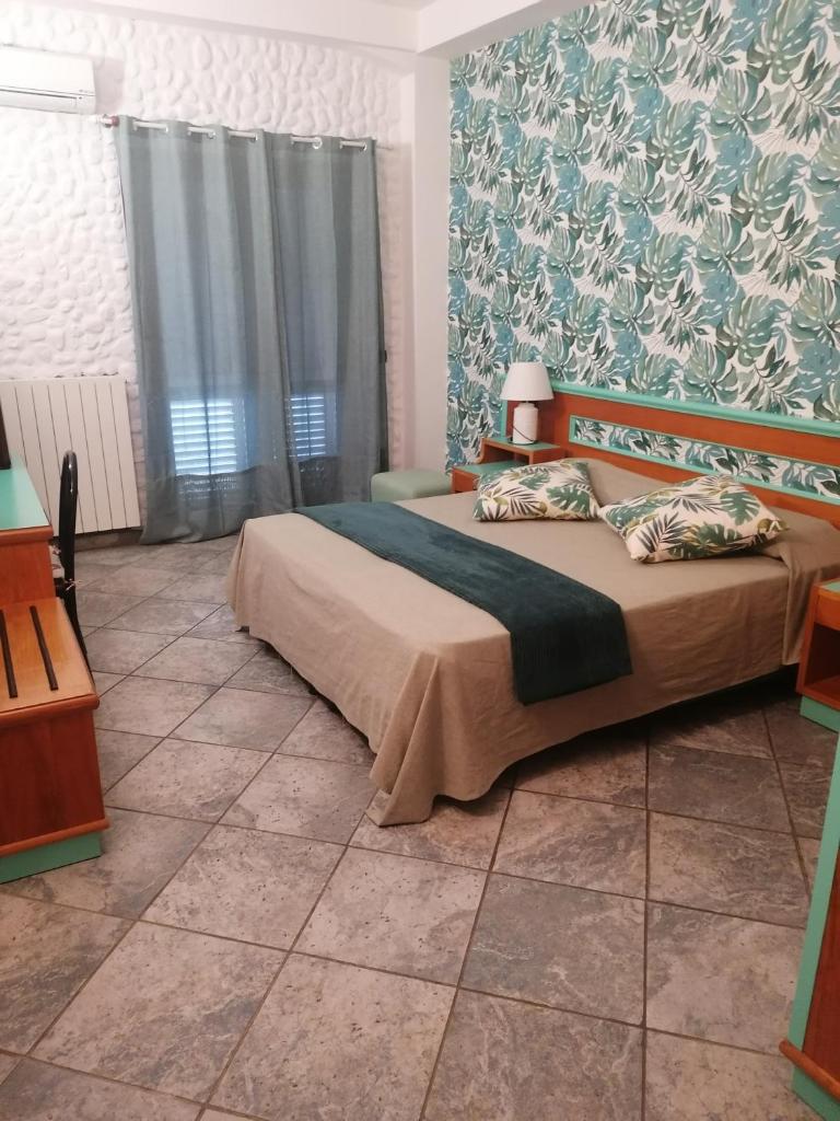 - une chambre avec un lit et un mur orné de fleurs dans l'établissement Hotel Esperia, à Piombino