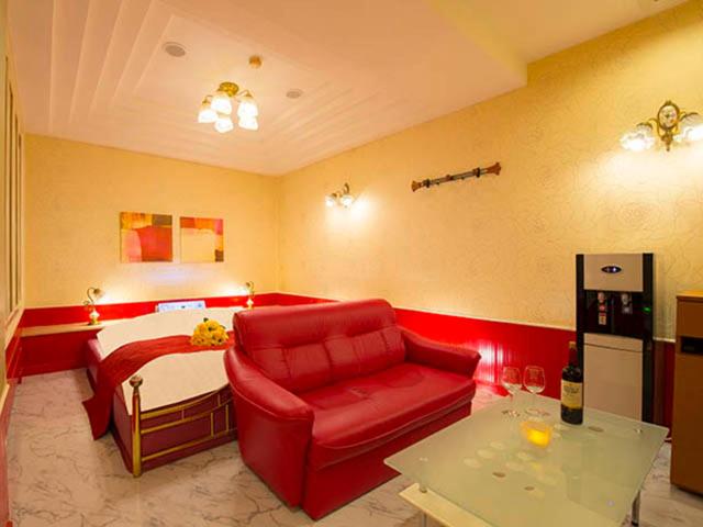 un salon avec un canapé rouge et un lit dans l'établissement かぼちゃの馬車 泉大津大人専用, à Izumiotsu