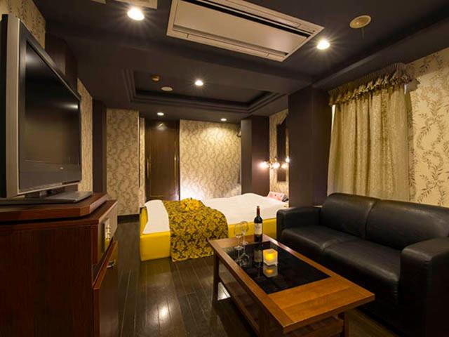 une chambre d'hôtel avec un canapé, un lit et une télévision dans l'établissement かぼちゃの馬車 泉大津大人専用, à Izumiotsu