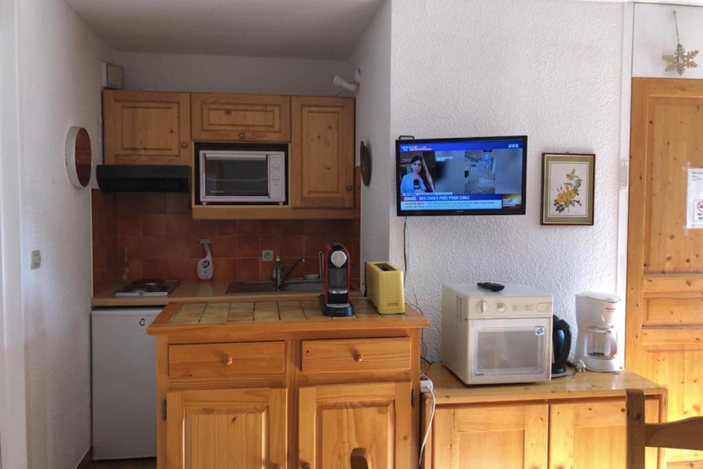 Il comprend une cuisine avec des placards en bois et une télévision murale. dans l'établissement Nice 37m near the center of La Salle-les-Alpes, à La Salle Les Alpes