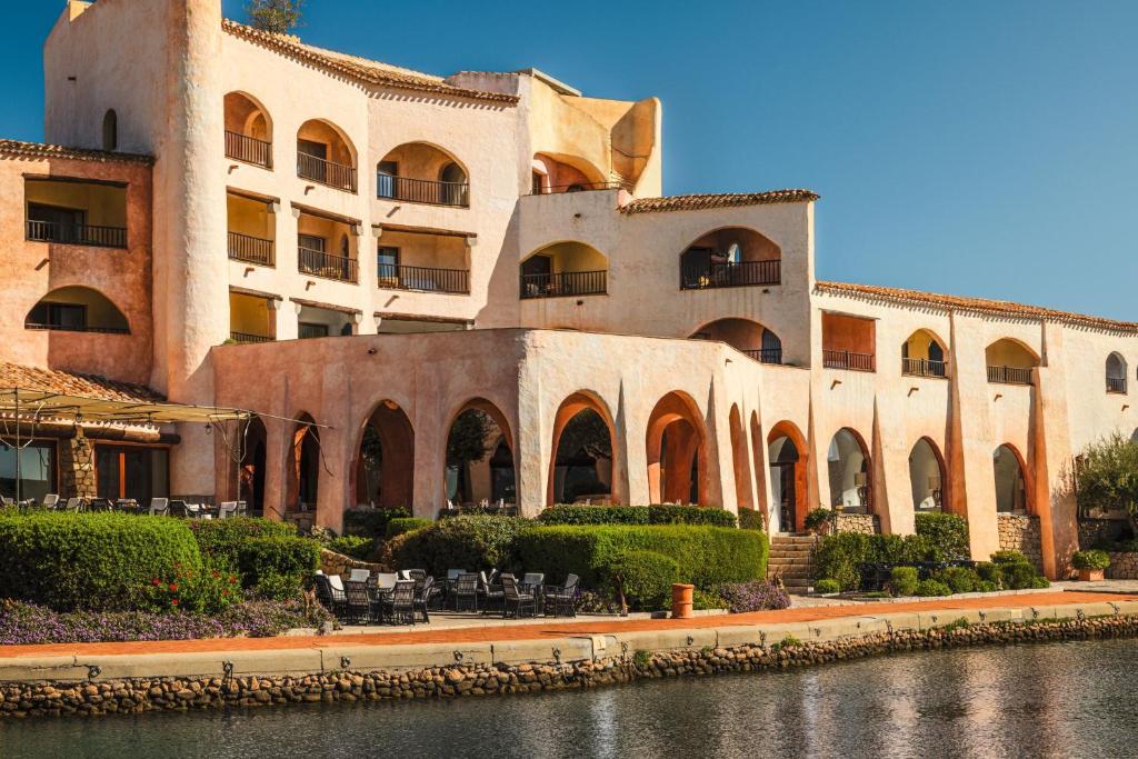un grand bâtiment avec une rivière en face dans l'établissement Hotel Cala di Volpe, a Luxury Collection Hotel, Costa Smeralda, à Porto Cervo