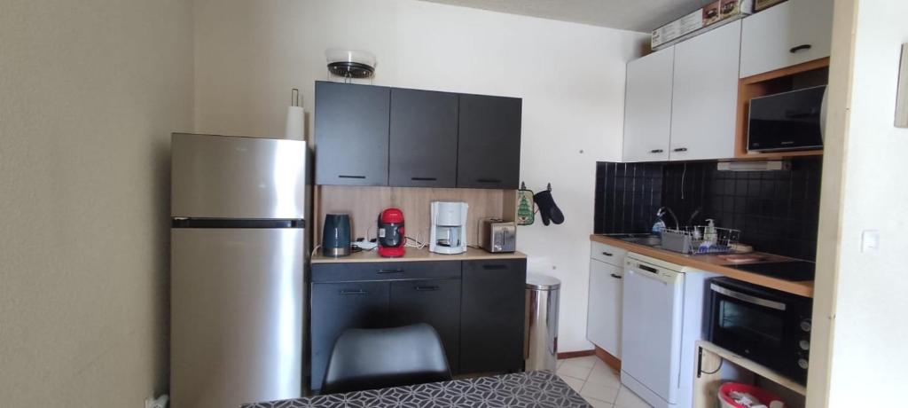 une cuisine avec un réfrigérateur en acier inoxydable et des armoires noires dans l'établissement Appart 4-6 pers au pied des pistes toutes saisons, à Molines-en-Queyras 11 autres photos