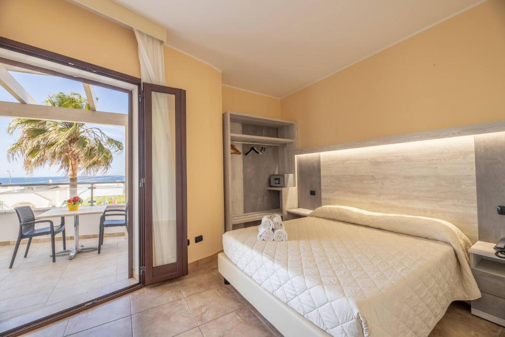 une chambre avec un lit et un balcon avec une table dans l'établissement Hotel Salento Mirfran, à Torre San Giovanni