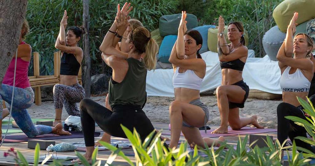 - un groupe de femmes faisant du yoga sur la plage dans l'établissement Residence Hotel Lu Nibareddu, à San Teodoro