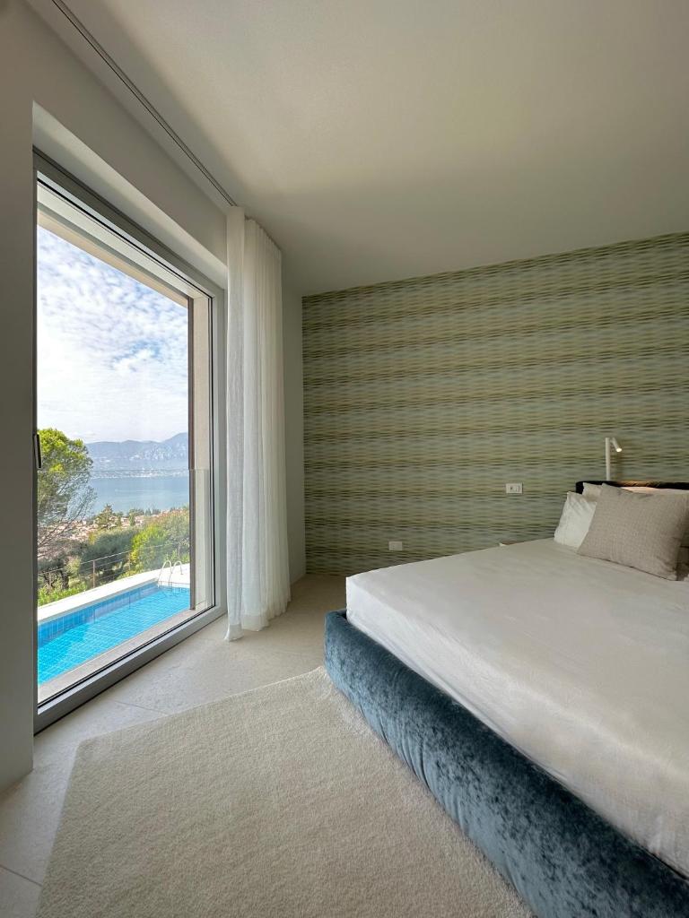 une chambre avec un grand lit et une grande fenêtre dans l'établissement Villa Montagna, à Torri del Benaco