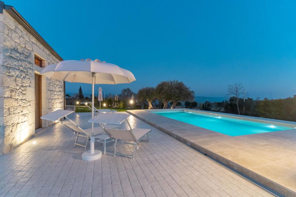 - une terrasse avec une table et un parasol à côté de la piscine dans l'établissement House Nicasia: villa con piscina, à Raguse