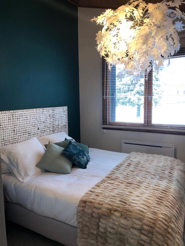 - une chambre avec un lit doté d'oreillers et d'un lustre dans l'établissement Maison autrans, à Autrans