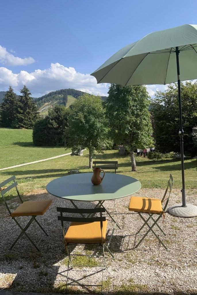 une table avec un vase et un parapluie dans l'établissement Maison autrans, à Autrans