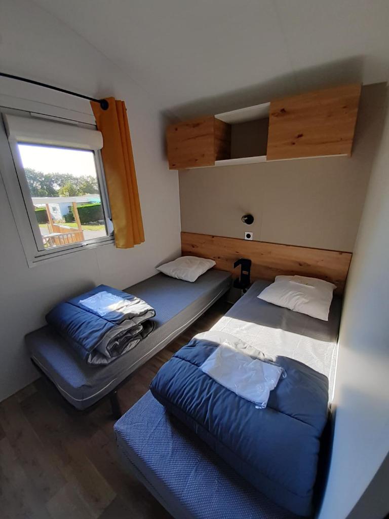 deux lits dans une petite pièce avec une fenêtre dans l'établissement Camping Les Brillas, à Les Moutiers