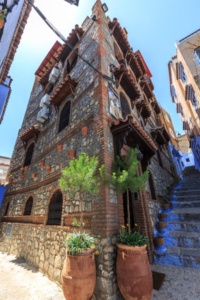 un bâtiment avec deux plantes en pot devant lui dans l'établissement Riad Gharnata, à Chefchaouen