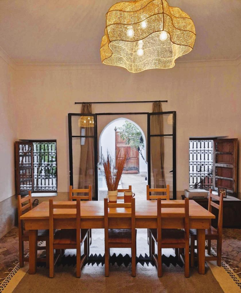 une salle à manger avec une table, des chaises et un lustre dans l'établissement RIAD SAMAH, à Marrakech