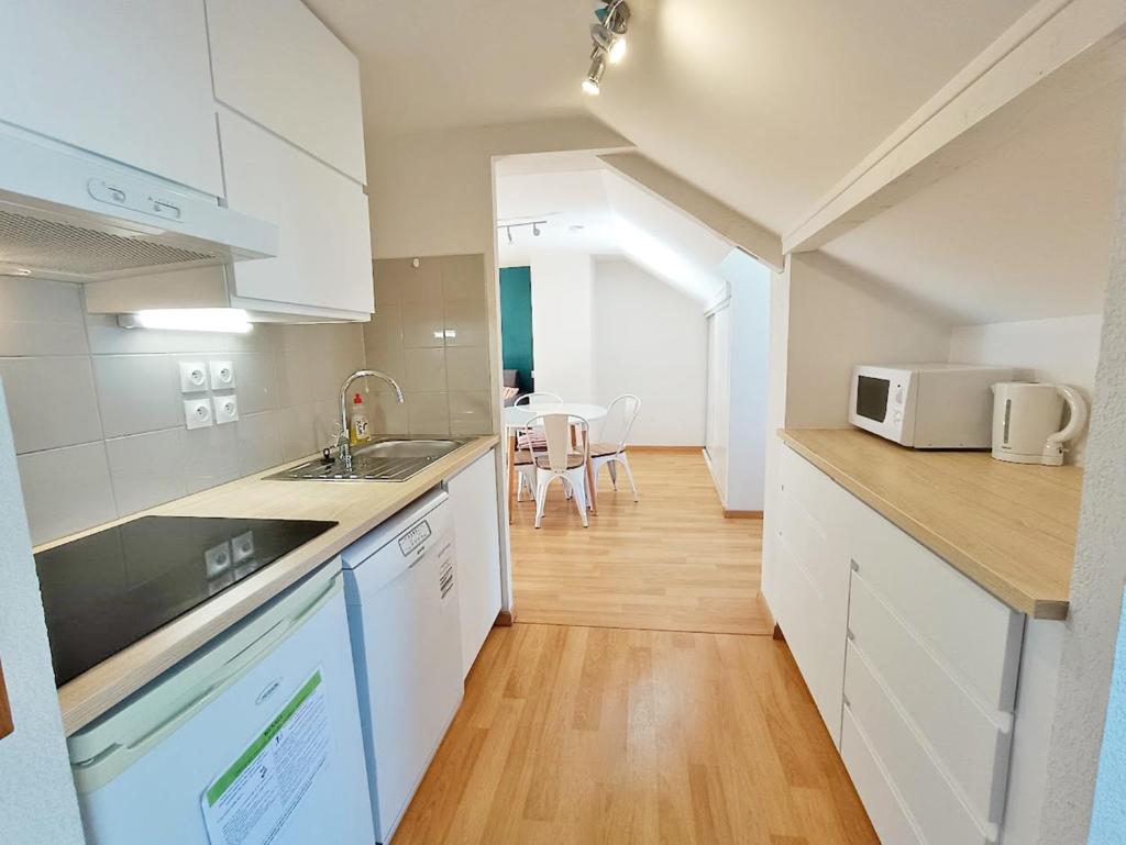 une cuisine avec un évier et un micro-ondes dans l'établissement L'Esquiros, studio, centre Luchon, casier à skis, wifi, ascenseur, 3 personnes, à Luchon