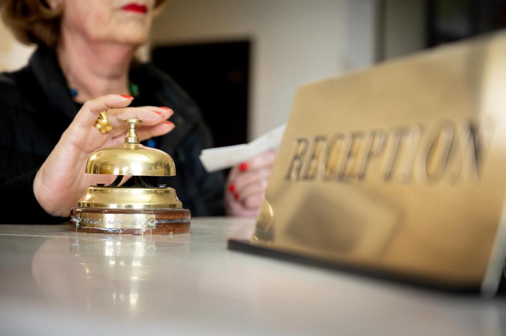 une femme assise à une table avec une cloche dorée dans l'établissement Hotel Sabbie d'Oro, à Giardini Naxos