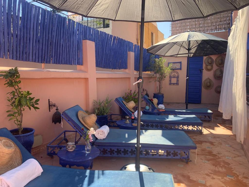 une terrasse avec des chaises bleues et un parasol dans l'établissement Riad Blue Berber, à Marrakech