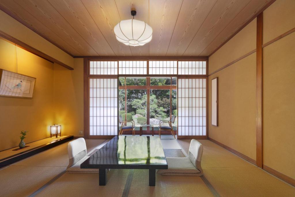 une salle à manger avec une table et des chaises et une grande fenêtre dans l'établissement Tokiwa Bekkan, à Toyooka