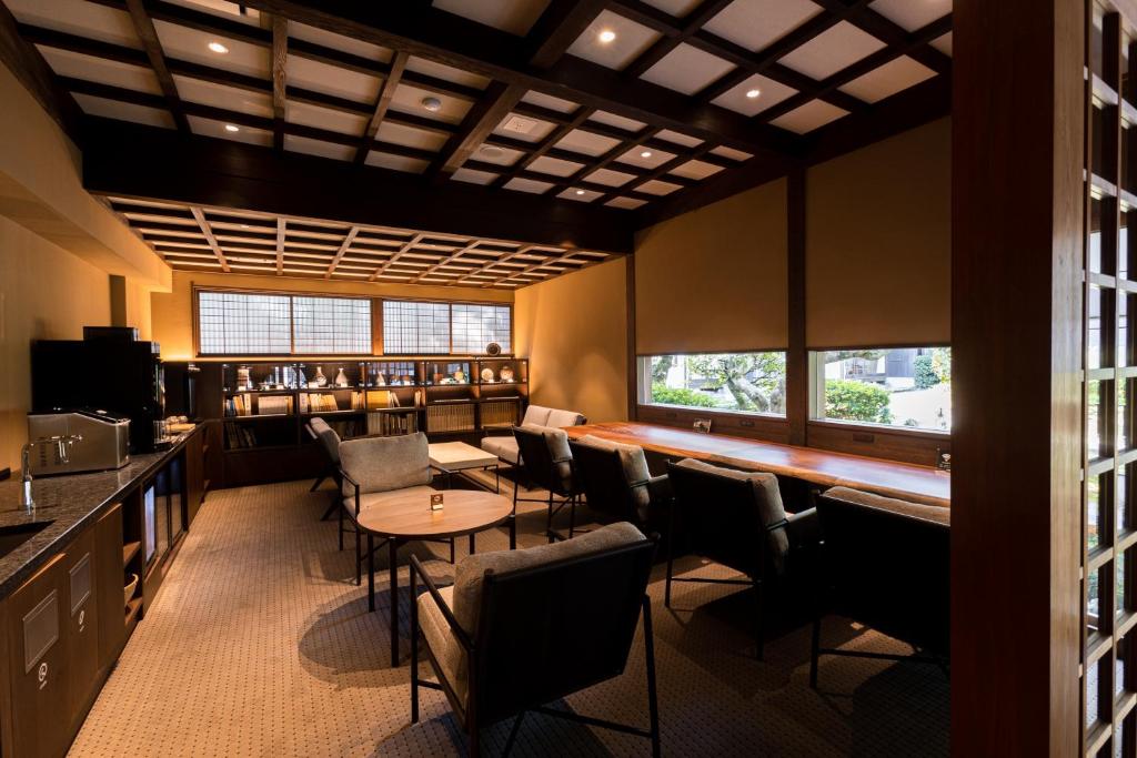une salle à manger avec une table, des chaises et des fenêtres dans l'établissement Tokiwa Bekkan, à Toyooka