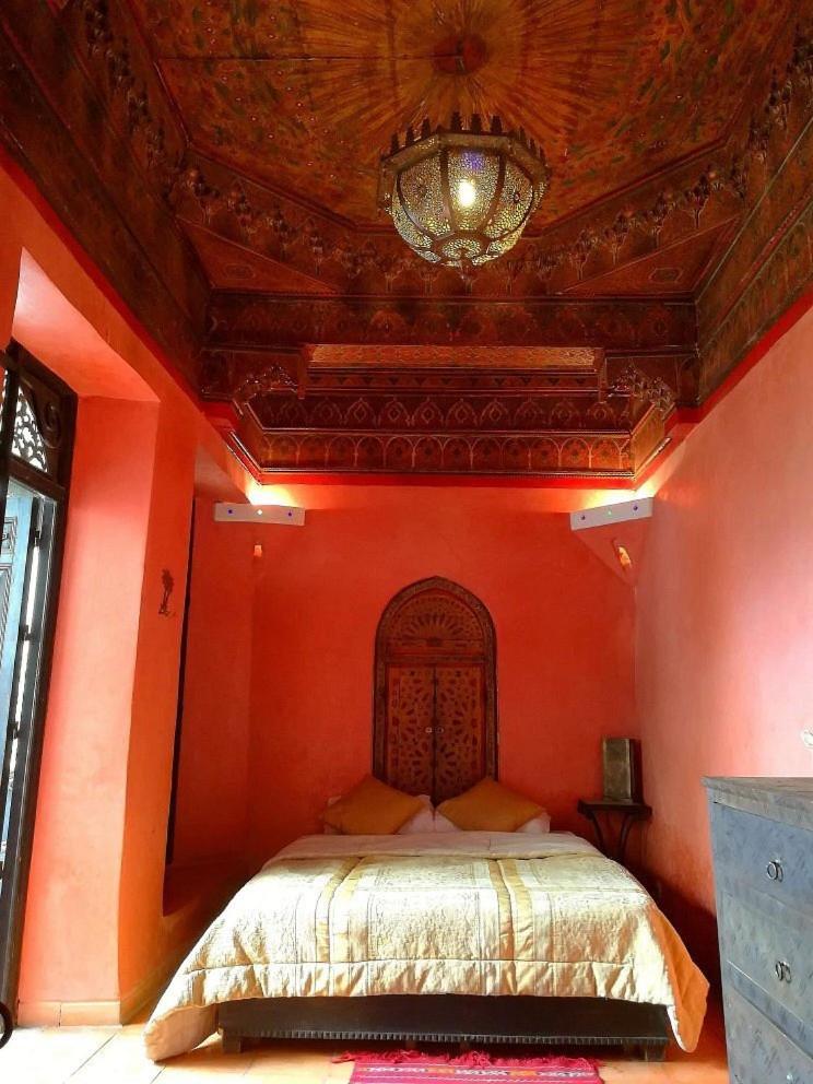 une chambre avec un grand lit avec un mur orange dans l'établissement Riad Sabbah, à Marrakech