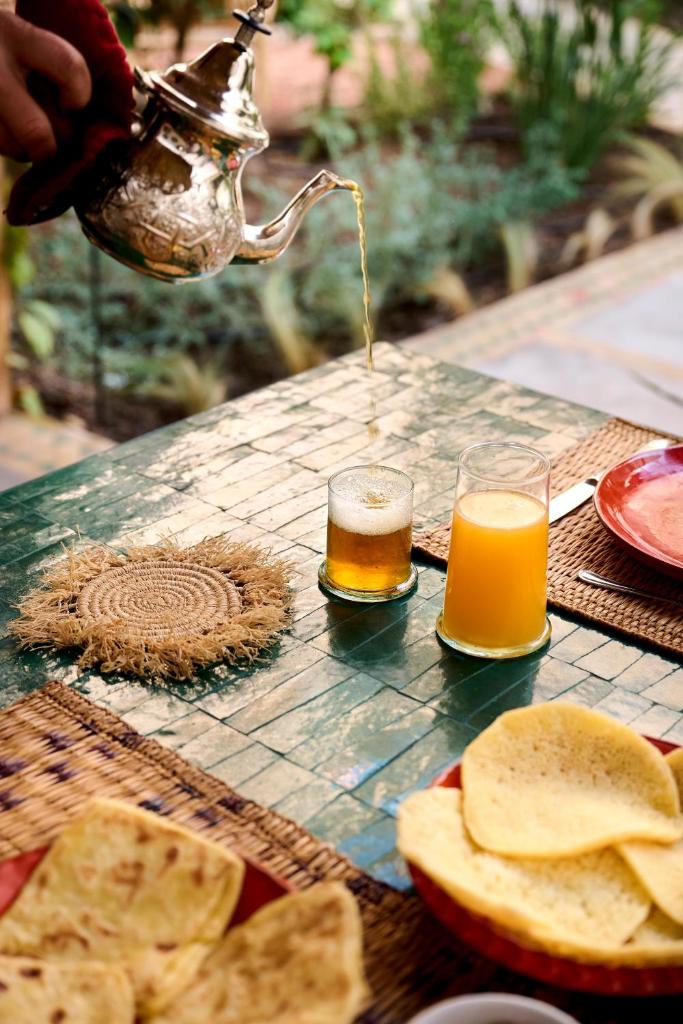 une personne tenant une bouilloire et deux verres de bière dans l'établissement Riad Dar Amanza en exclusivité avec 4 chambres au coeur de la médina, à Marrakech