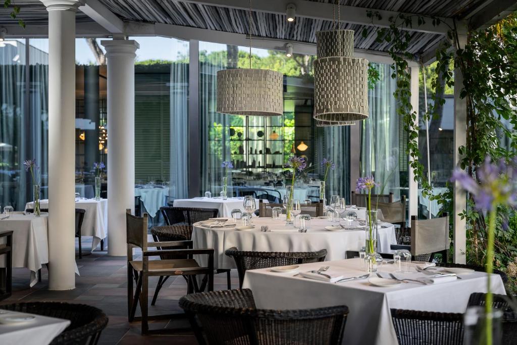 une salle à manger avec des tables et des chaises blanches dans l'établissement Villa Regina - MarePineta Resort, à Milano Marittima