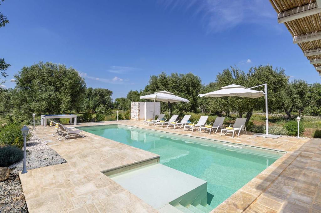 une piscine extérieure avec des chaises et des parasols dans l'établissement Villa Trullo Acquaro by Villa Plus, à Ostuni