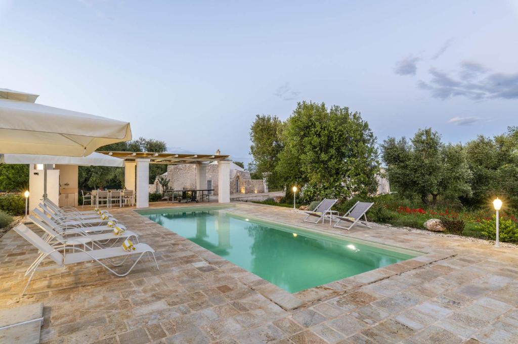 une piscine avec des chaises longues et un parasol dans l'établissement Villa Trullo Acquaro by Villa Plus, à Ostuni