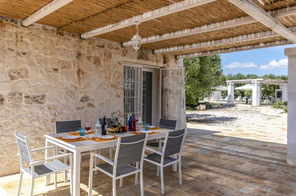 - un coin repas extérieur avec une table et des chaises blanches dans l'établissement Villa Trullo Acquaro by Villa Plus, à Ostuni