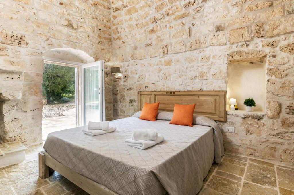 une chambre avec un grand lit dans un mur de pierre dans l'établissement Villa Trullo Acquaro by Villa Plus, à Ostuni