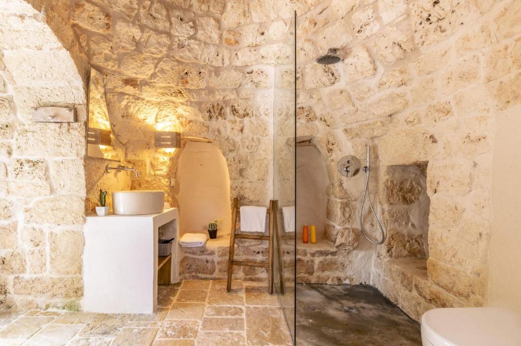 La salle de bains est pourvue d'une douche et d'un mur en pierre. dans l'établissement Villa Trullo Acquaro by Villa Plus, à Ostuni