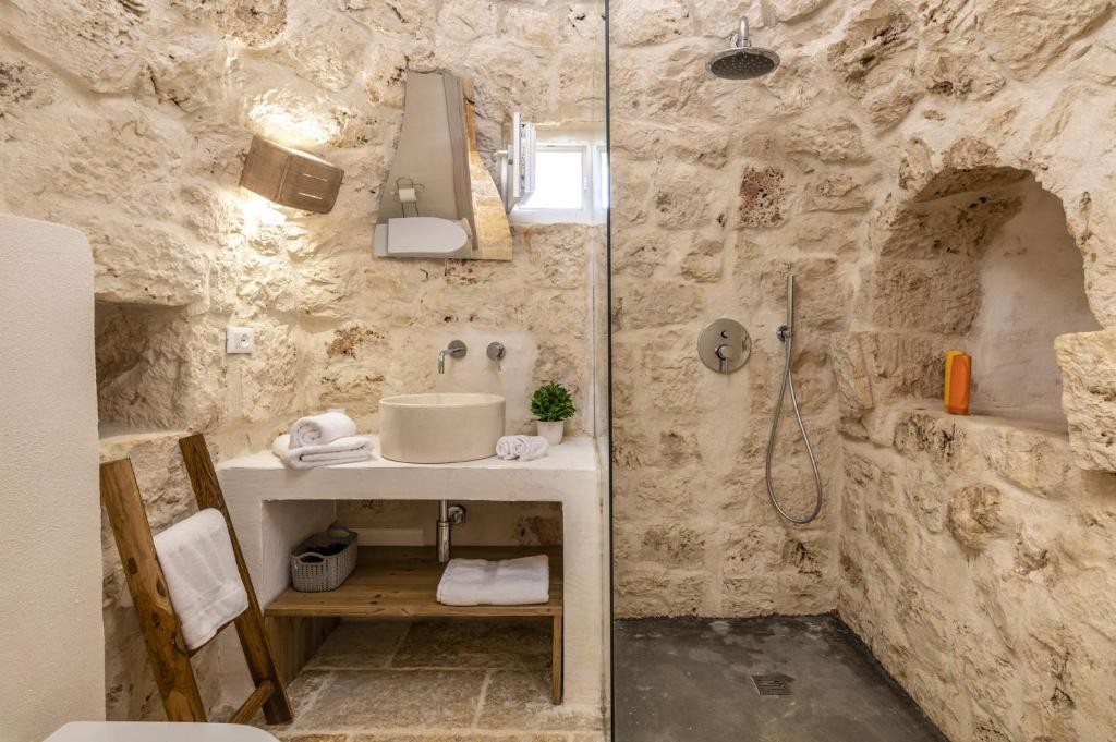 La salle de bains en pierre est pourvue d'un lavabo et d'une douche. dans l'établissement Villa Trullo Acquaro by Villa Plus, à Ostuni 22 autres photos