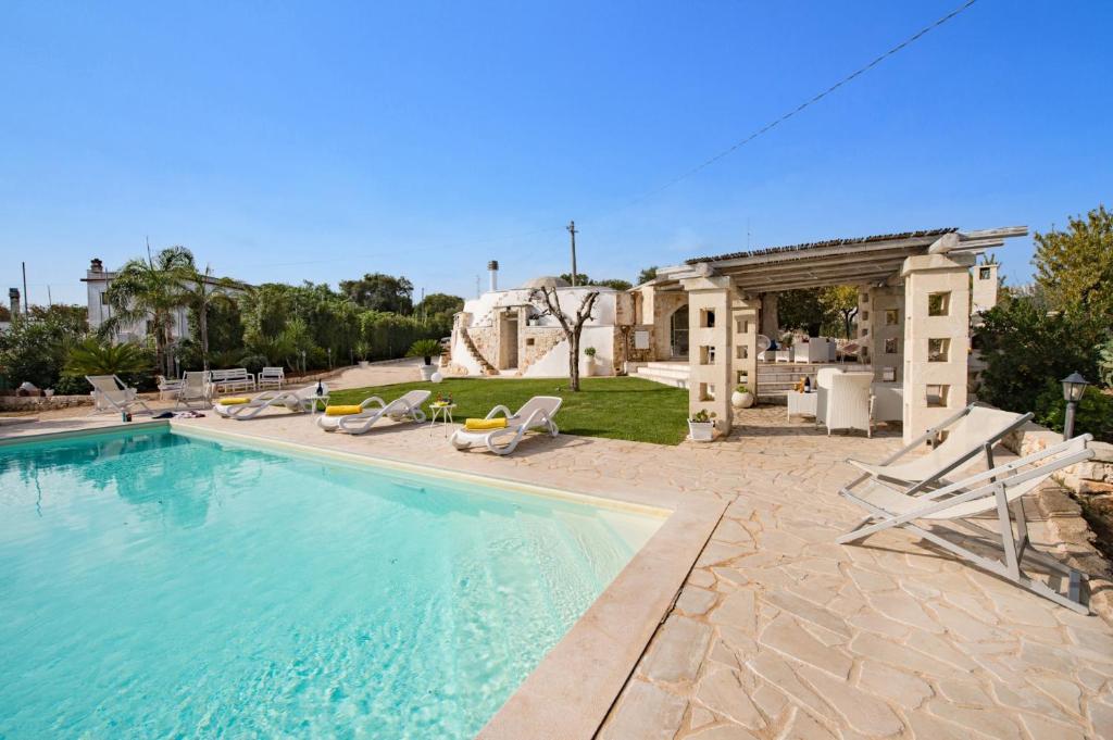 une grande piscine avec des chaises et une maison dans l'établissement Villa Trullo Saraceno by Villa Plus, à Ostuni 8 autres photos