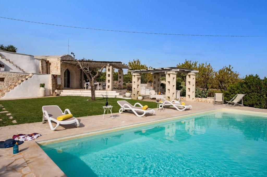 une piscine avec des chaises et une maison dans l'établissement Villa Trullo Saraceno by Villa Plus, à Ostuni