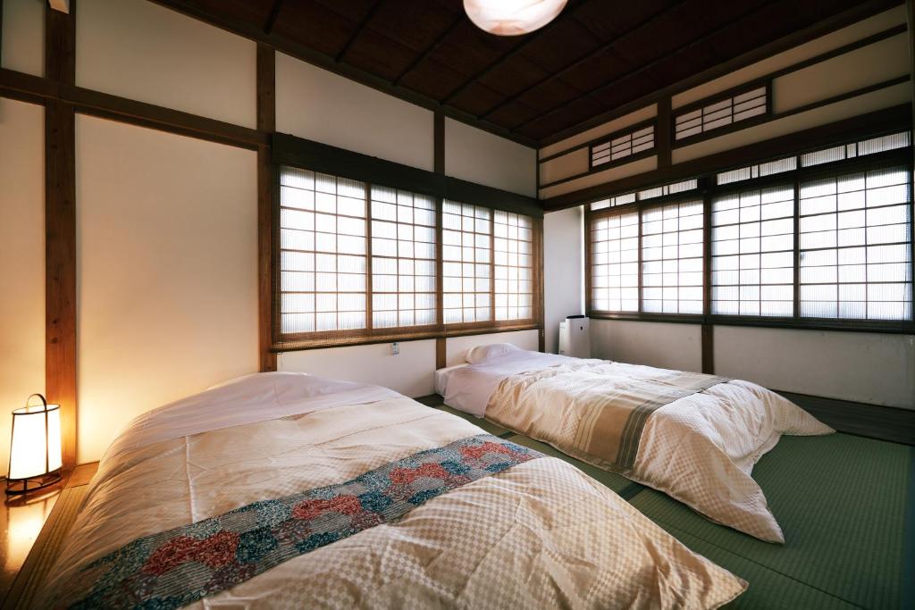 deux lits dans une chambre avec deux fenêtres dans l'établissement 町住客室 秩父宿, à Chichibu 37 autres photos
