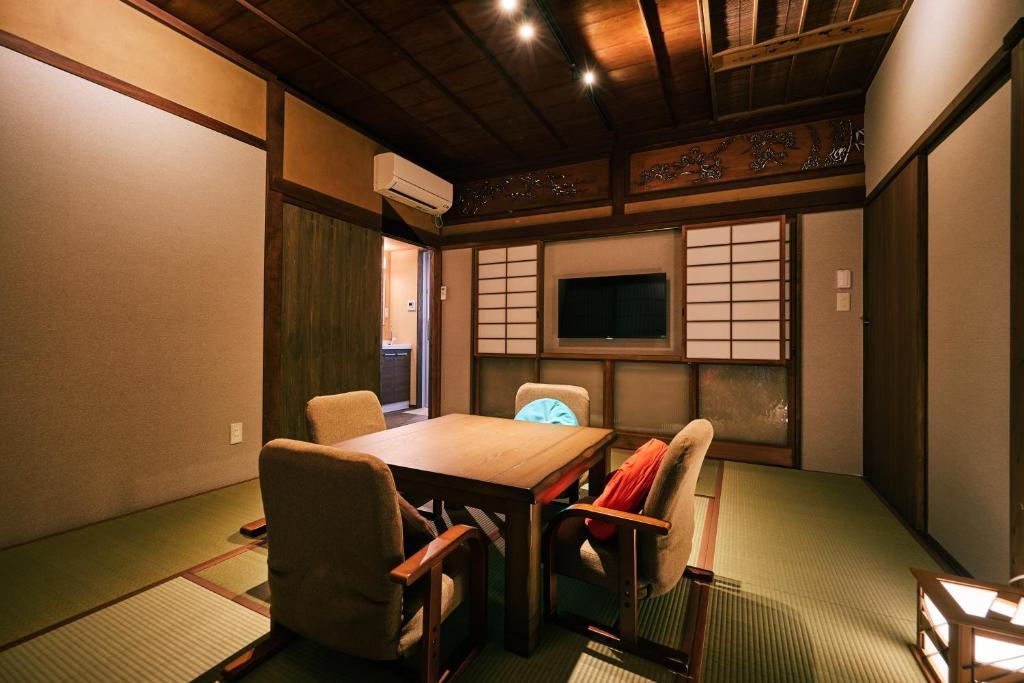 une pièce avec une table, des chaises et une télévision dans l'établissement 町住客室 秩父宿, à Chichibu